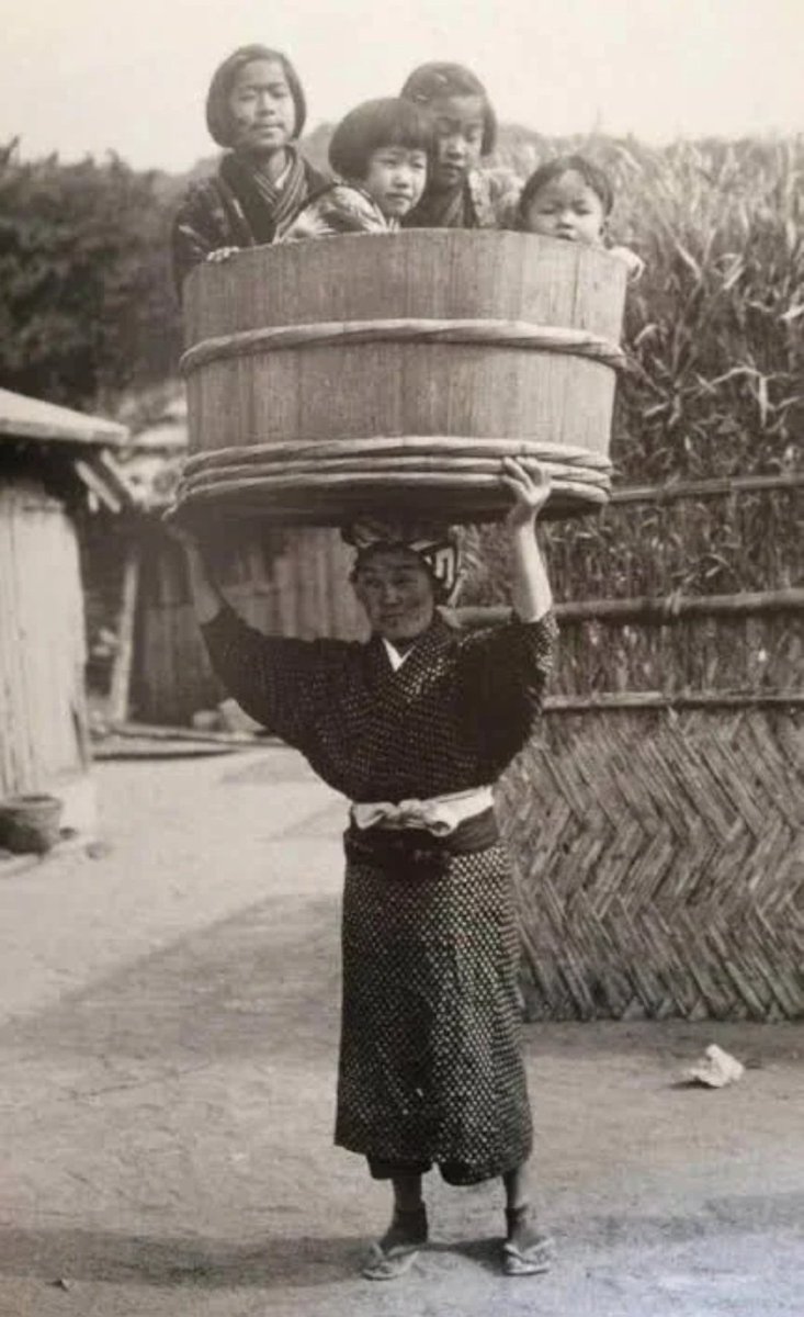 Une femme japonaise transportant ses enfants dans un sceau, vers 1900.