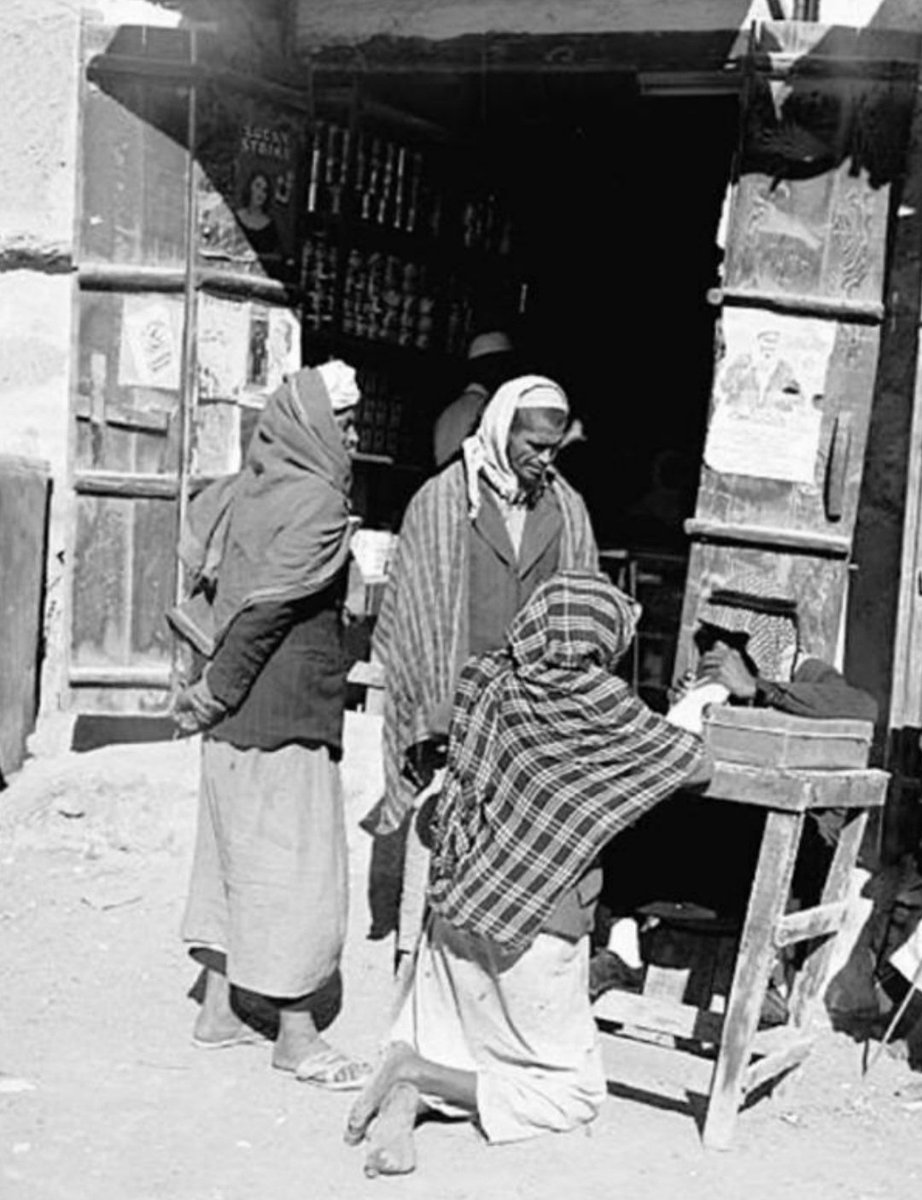 من ارشيفي المصور: صورة نادرة التقطت في الدمام في شتاء 1954م لأحد كتاب العرائض او من يسمون ب "العرضحالجية" وهو يمارس مهنته امام دكاني يوسف بن عبدالعزيز المعيبد ومحمد بن محمد الدوسري