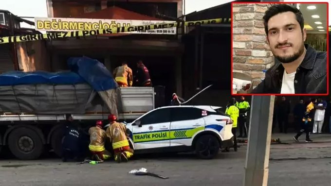 Scene at a crash site in front of a building with crime scene tape reading Decirmen something police tape across it showing a large truck with covered load and emergency personnel in yellow suits working around a white and blue police traffic vehicle with yellow stripes heavily damaged and collided into the truck side with a red generator and cables nearby and an inset portrait of a young man with short hair and beard wearing a black shirt