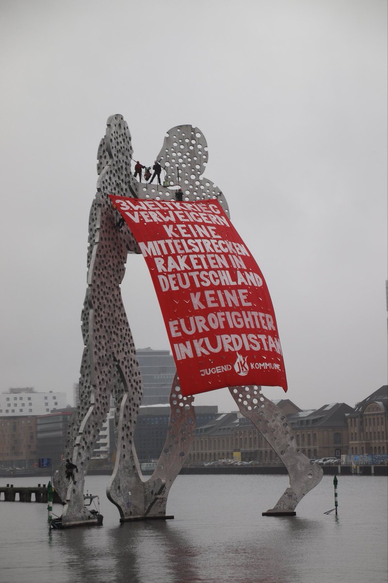 Vor einem Jahr, im November 2024, hat die Jugendkommune ein riesiges Banner gegen die Stationierung von Mittelstreckenraketen in der BRD und gegen Eurofighter in Kurdistan am „Molecule Man“ in der Berliner Spree gehisst. Das war eine schöne Aktion!