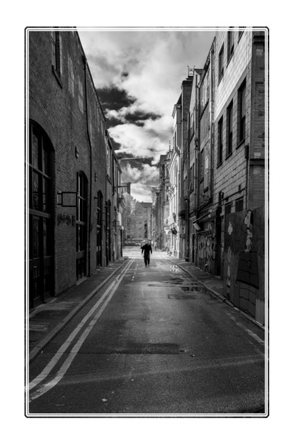 photos_dsmith's tweet image. A young man walks down the middle of an #alley in the #centre of #Manchester #England in #blackandwhite. The #contract of the #19thcentury #architecure of the #smallbusinesses and the #sky highlight the #autumn #weather of this day. #blackandwhitephotography #PhotographyIsArt