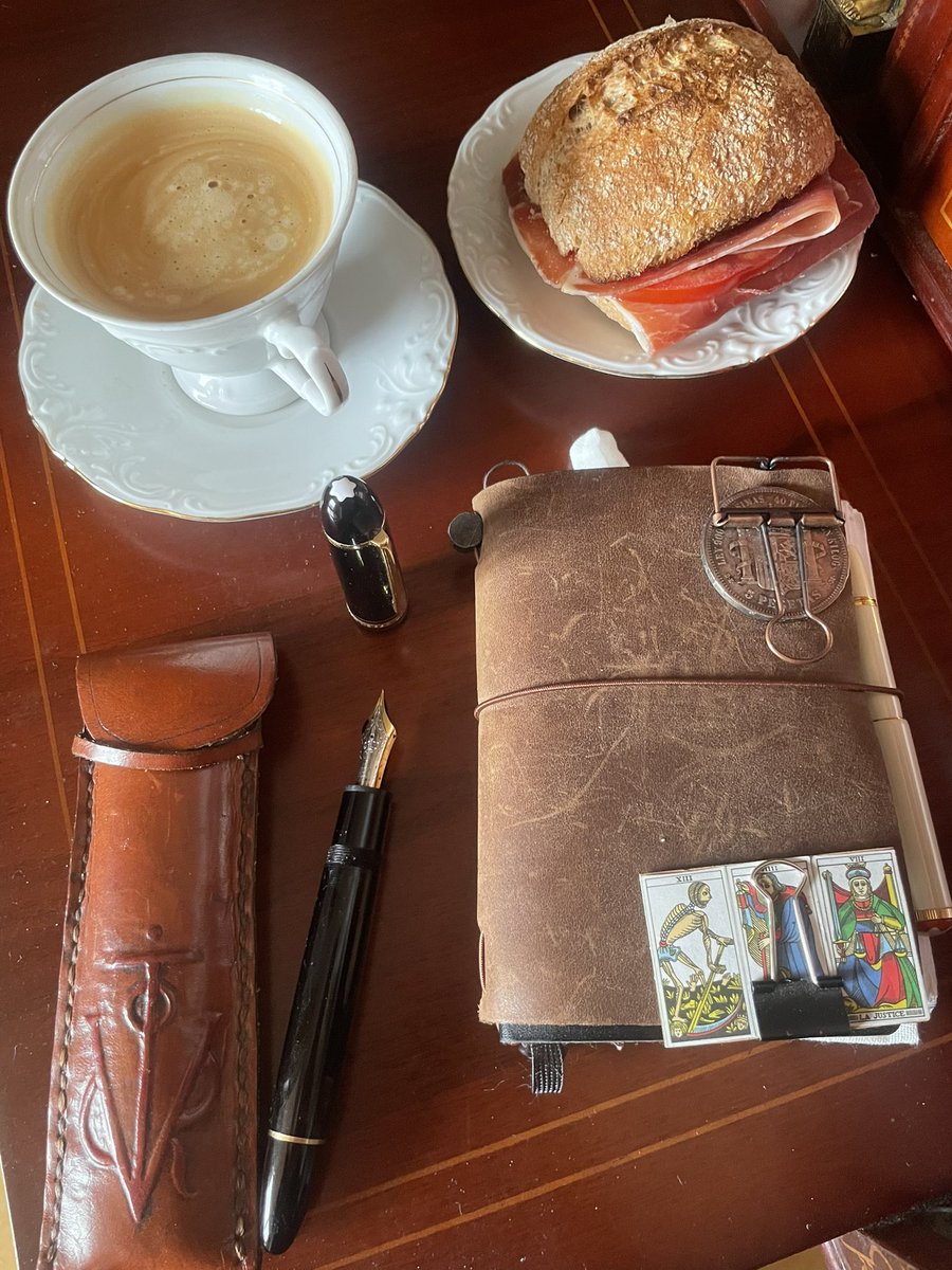 ⭕️Círculø del Escribä 📜

El café humea como un presagio antiguo. En la superficie se dibuja un remolino que parece decirnos: escríbeme, muchacho, que hoy la historia quiere que la escribas tú. La pluma descansa a la derecha, lista para clavar su filo dorado sobre el papel, igual