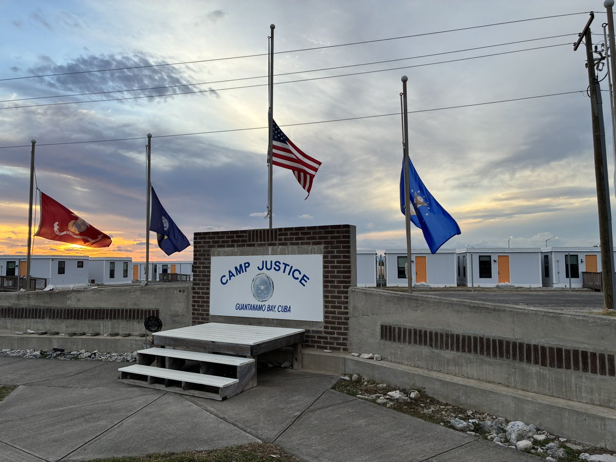 carolrosenberg's tweet image. Good afternoon from Camp Justice at Guantanamo Bay, Cuba, where the flags are at half-mast for Dick Cheney above the faded war court emblem. They&apos;re doing pretrial arguments today in the USS Cole case, including  a new defense bid to block the defendant&apos;s 2007 tribunal.