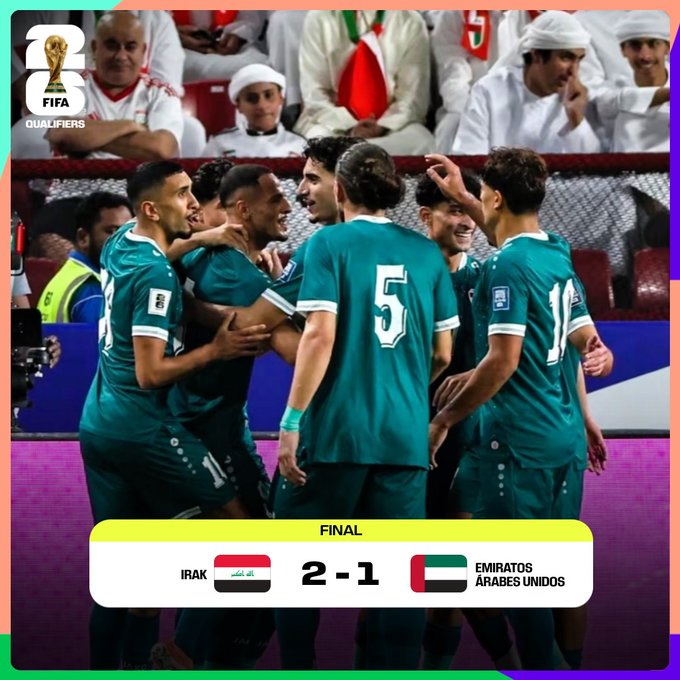 Group of male soccer players in green jerseys with numbers like 5 celebrating a victory by hugging and raising arms in a stadium with spectators in background wearing white and red attire some with headscarves under bright lights and banners yellow text overlay shows Irak 2-1 Emiratos Árabes Unidos final match labels.
