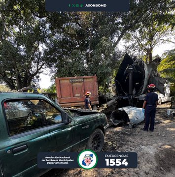First image shows a severely damaged tanker truck with its side torn open, insulation exposed and hanging, situated on a dirt road surrounded by trees and palm plants under a clear sky. Second image depicts the wrecked truck cab crumpled against a red container, with two firefighters in yellow helmets and uniforms standing nearby inspecting the debris on a rural roadside with trees in the background. Third image captures a female firefighter with hair in a ponytail, wearing a dark uniform, leaning into the open door of an emergency vehicle, possibly providing aid inside. Fourth image features a male firefighter in uniform and helmet, positioned at the open door of the emergency vehicle, appearing to assist or communicate with someone inside the cabin.
