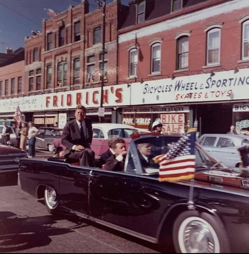 JFK passing Fridrich’s bicycle shop on Lorain Ave en route to St. Edward’s High School from <a href="/CLEPublicSquare/">CLE Public Square</a> 
October 19, 1962 🚲