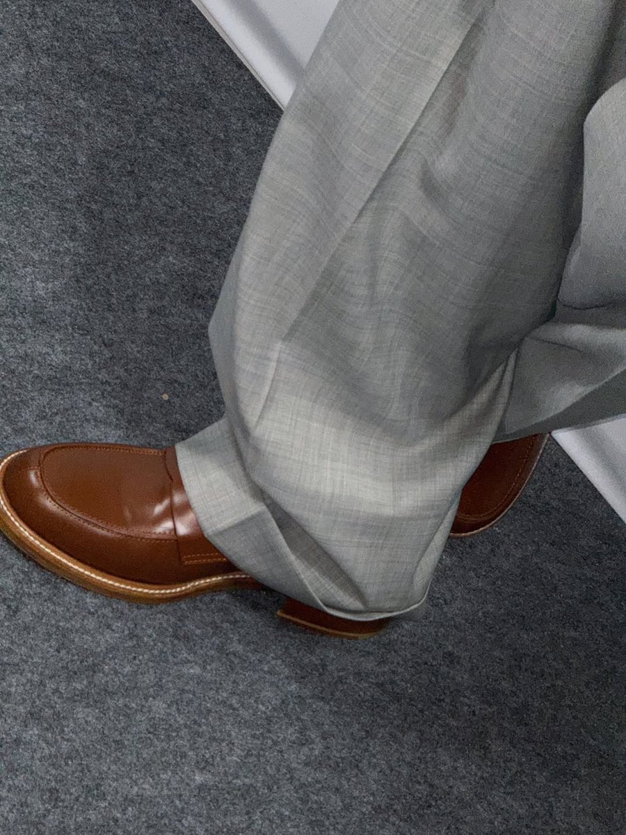 Hanbing's tweet image. Arms spread wide like I’m about to take flight! The overhead angle captures my pure joy as I stand before the elegant backdrop. My brown vest and grey trousers complete this vintage-inspired look, while my hat adds that perfect finishing touch to the whole ensemble.