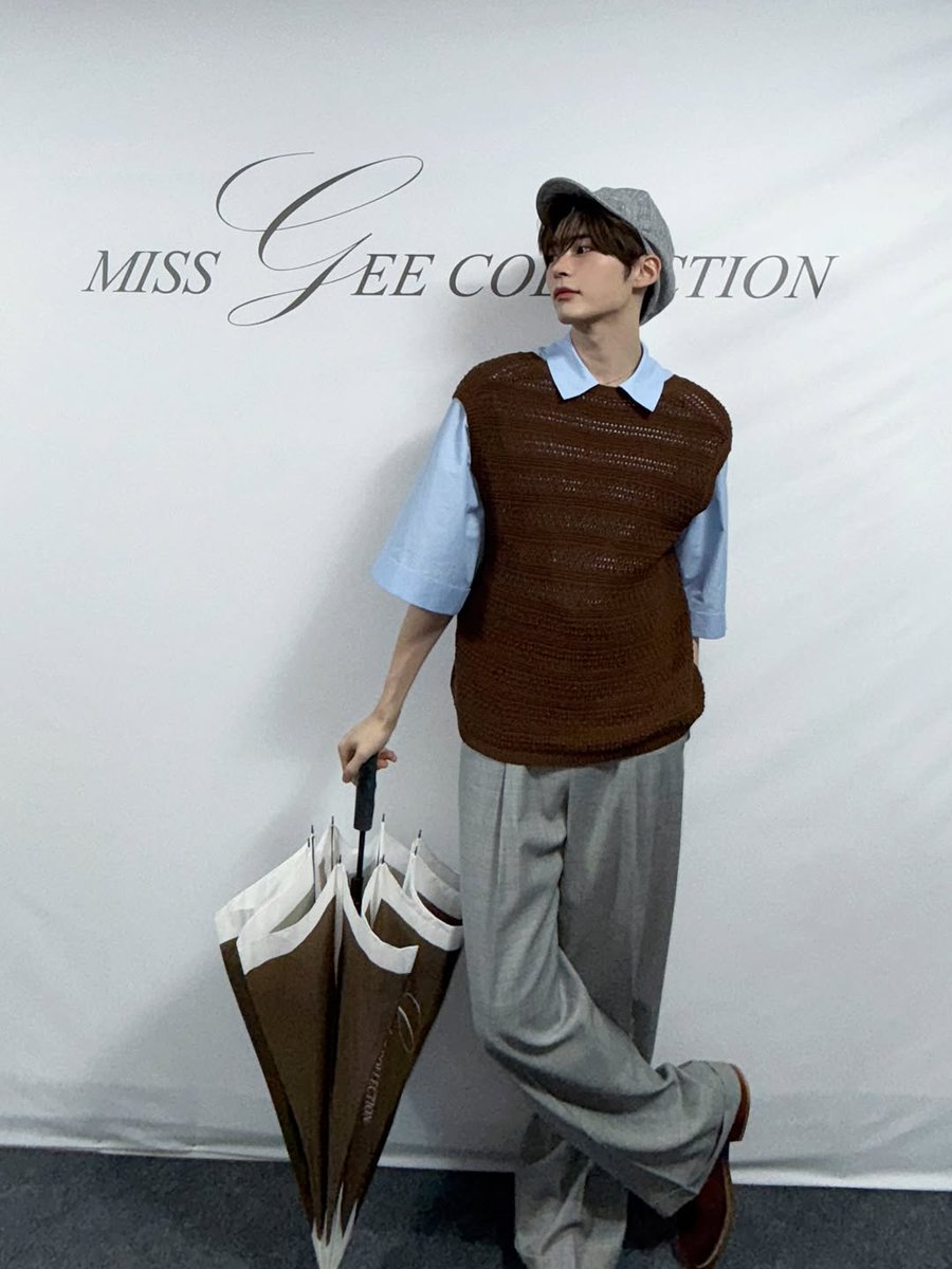 Hanbing's tweet image. Arms spread wide like I’m about to take flight! The overhead angle captures my pure joy as I stand before the elegant backdrop. My brown vest and grey trousers complete this vintage-inspired look, while my hat adds that perfect finishing touch to the whole ensemble.