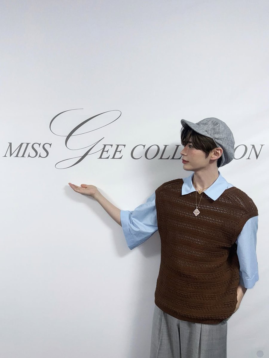 Hanbing's tweet image. Posing next to the MISS 𝓖EE COLLECTION wall, I can’t help but present it with pride. My hand gestures toward the elegant lettering as if I’m introducing you to something special. Being part of this fashion show made me feel like I truly belong here.