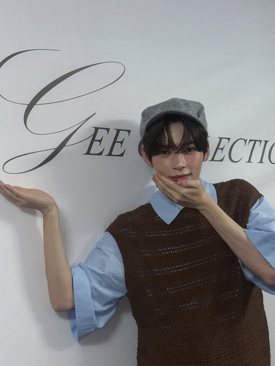 Hanbing's tweet image. Posing next to the MISS 𝓖EE COLLECTION wall, I can’t help but present it with pride. My hand gestures toward the elegant lettering as if I’m introducing you to something special. Being part of this fashion show made me feel like I truly belong here.