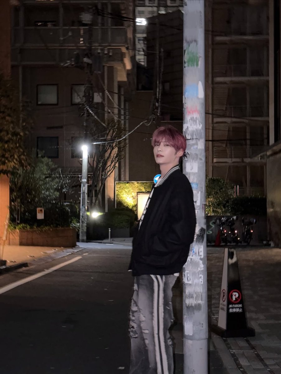 Hanbing's tweet image. Against this pole at night, pretending I’m in a music video. I’ve got my hands in my pockets, head tilted, and the street is my stage. If you catch me lost in thought under the city lights, know I’m probably humming my favorite song and plotting dance moves.