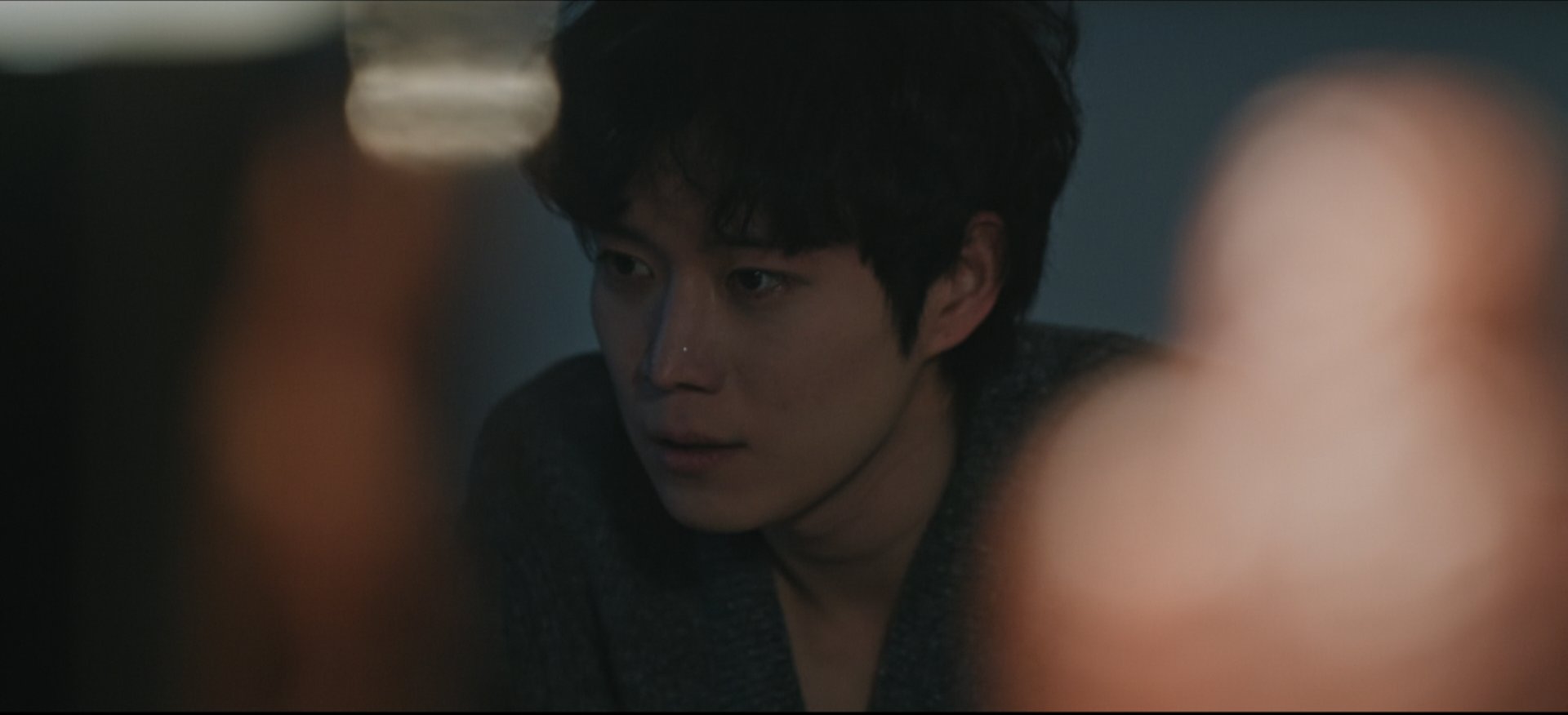 눈가에 눈물을 머금고 허탈하게 웃고 있는 윤준서의 스틸컷