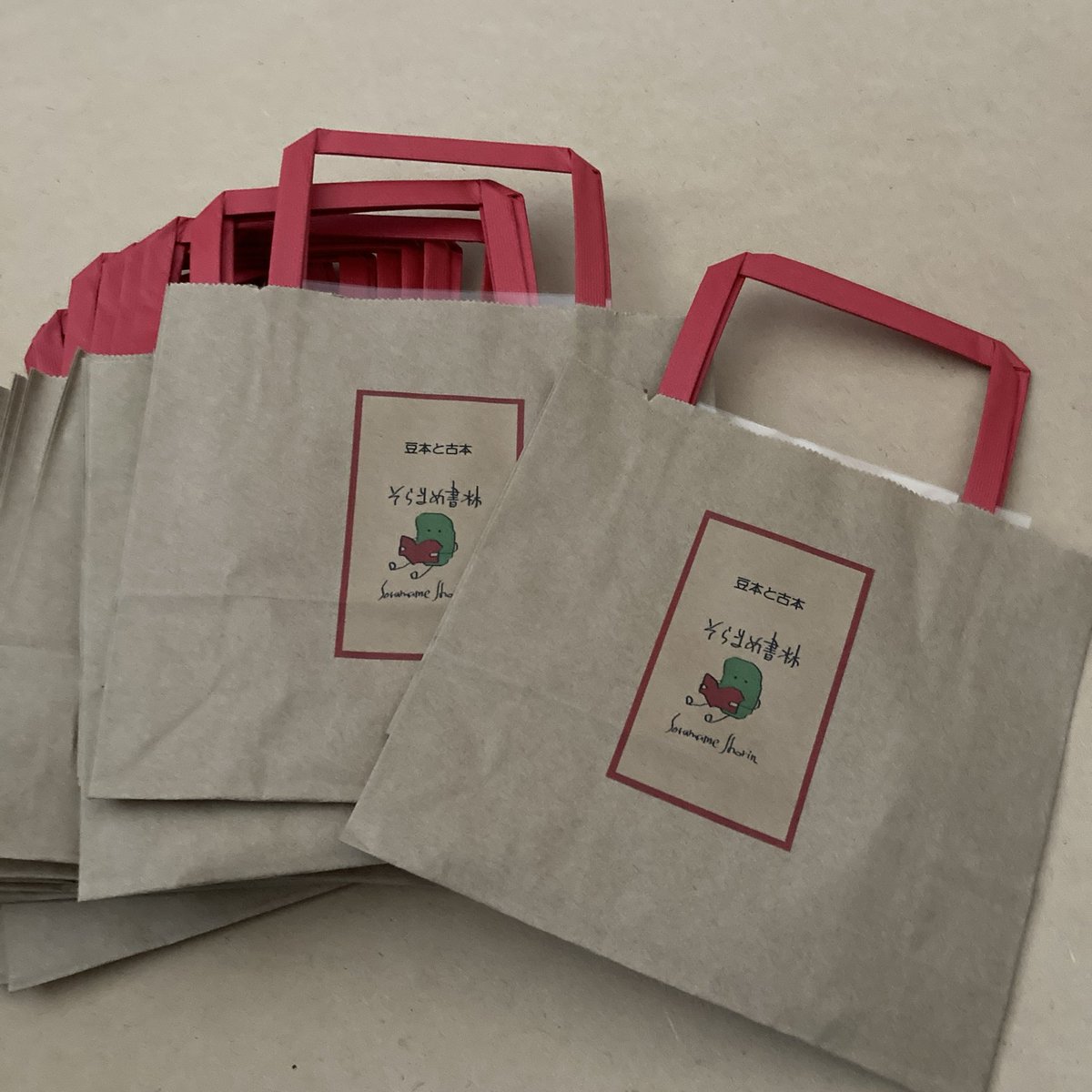 持ち手が赤くてかわいい紙袋を見つけたので、今年はそれを使ってオリジナルバッグを作りました。豆本お買い上げの方はこの袋にお入れします(^^)ただいま増産中！手提げ袋作っているヒマがあったら豆本作らないとなのですが(^◇^;)