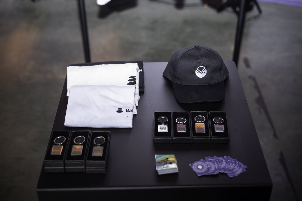 活动周边桌，上面有 Safe 钥匙扣、Gnosis 猫头鹰帽和 Balancer T 恤