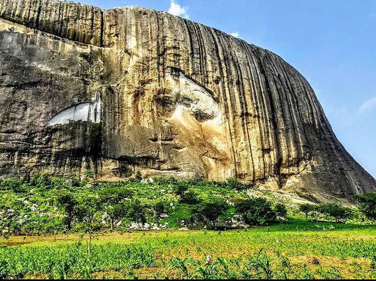 geologyBits's tweet photo. 🟥 ⛏️ Zuma Rock
is a towering 725-meter-high inselberg rising dramatically 300–400 m above the surrounding savanna plains about 45 km north of Abuja, Nigeria. 

❤️ 🔁 #ZumaRock #NigerianInselberg                                                                                          

🎞️ @Taythestoryteller
▶️ This massive, near-vertical monolith consists of coarsely porphyritic biotite granite and granodiorite of the Pan-African Older Granite suite (c. 600–650 Ma), characterized by large pink K-feldspar phenocrysts up to 10 cm long set in a grayish groundmass.

Its distinctive near-vertical jointing and exfoliation sheets create bold, ribbed faces, while the famous white scar resembling a human face on its northern flank results from differential weathering along a lighter-colored pegmatite dike.

▶️ Zuma Rock formed during the Pan-African orogeny (~650–550 Ma) when collision between the West African Craton and the Saharan Metacraton generated deep-crustal granitic plutons.

After emplacement at depth, prolonged uplift and erosion stripped away overlying country rock, leaving the resistant granite core standing as an inselberg.

Subsequent deep chemical weathering under tropical climates preferentially eroded joint planes and produced thick regolith, accentuating the monolith’s steep, domed profile through long-term exfoliation and spheroidal weathering.