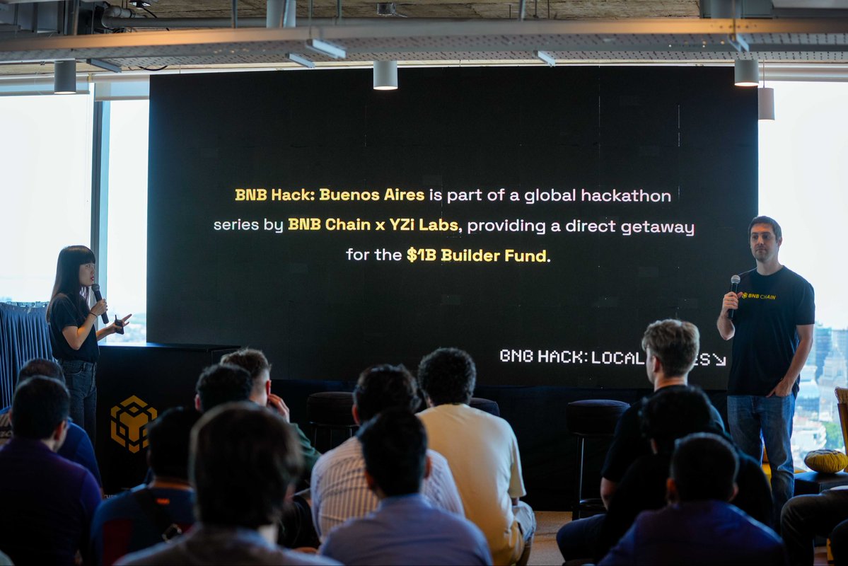 演讲者在 BNB Hack 布宜诺斯艾利斯活动的舞台上演讲，台下有观众，屏幕展示全球黑客松系列说明