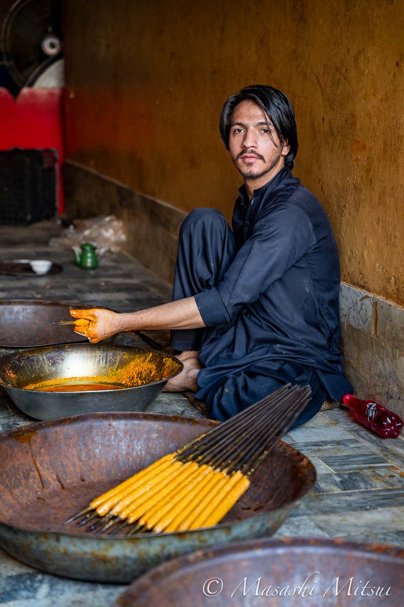 パキスタンの街角でシークケバブを作るイケメンの若者。タレで味をつけたひき肉を鉄の棒に巻き付けて炭火で焼くシークケバブは、「肉食の国」パキスタンを代表する肉料理のひとつだ。