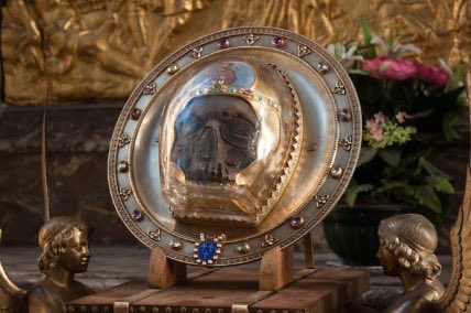 DanielLutaaya's tweet photo. It is not witchcraft.
She is simply speaking to her ancestors. 
Catholics do it too, they have specific Ancestors/Jajja’s whom they call saints that deal with various issues. Just like we have balubaale in Buganda who mediate between us and the creator, catholics also have saints(dead great men and women) who mediate between them and YhWh.

Since these Jajjas died in a war, I think she is asking them to rise up and fight.
What she is doing is exactly what the catholics do, only difference is that the religion she is practicing is black and colonialism taught us to hate ourselves.

Below is the head of Saint Catherine of Sienna, Pope Francis kissing the clotted blood of St Janarius, the head of St John the baptist and the skeleton of St Boniface.

All these Ancestors/Saints or Jajjas of the catholic church are lying in Cathedrals world over and people pray to them.

If what Hajjat Namyalo did is witchcraft, then this too should be categorized as witchcraft.