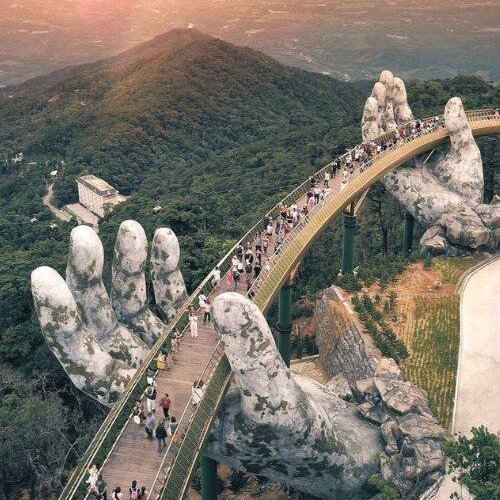 The Golden Bridge is a pedestrian bridge in Vietnam's Ba Na Hills near Da Nang, notable for its unique design where two giant, mossy hands hold the walkway. Completed in 2018, it is 150 meters long and sits 1,400 meters above sea level, offering panoramic views of the  mountains.