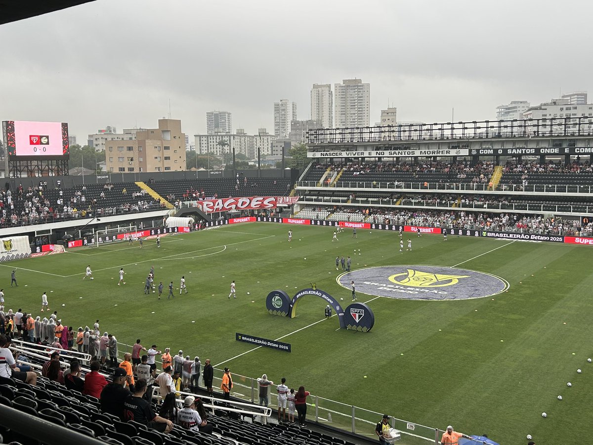 Chove na Vila Belmiro. Jogadores do São Paulo no aquecimento no gramado.