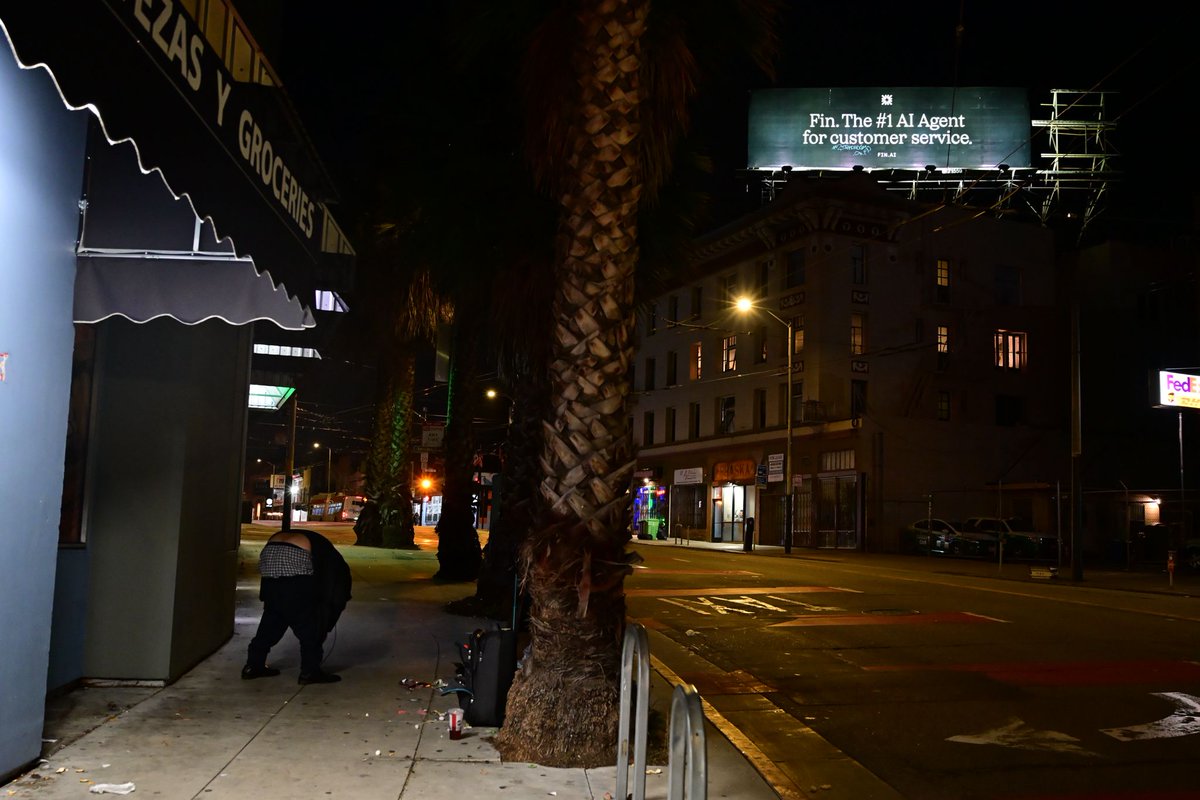 Clara_Gold's tweet image. SF is where the AI future shines from a billboard and the human present collapses on the sidewalk below it.