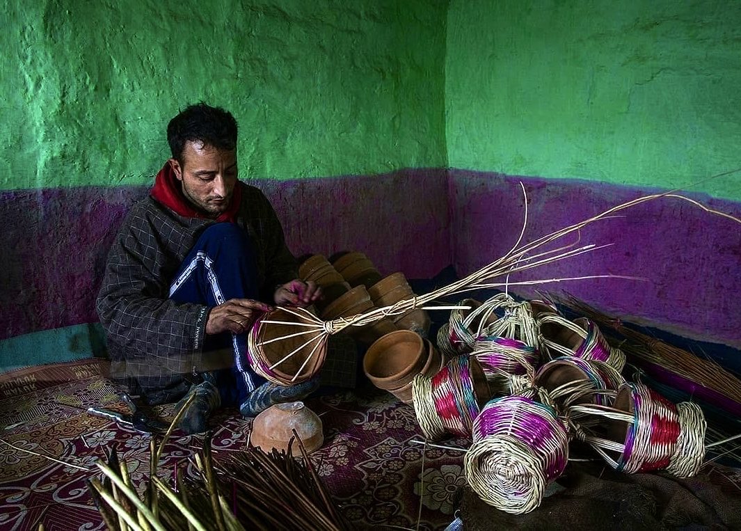 A craftsman weaves a kangri at a village in Kulgam.