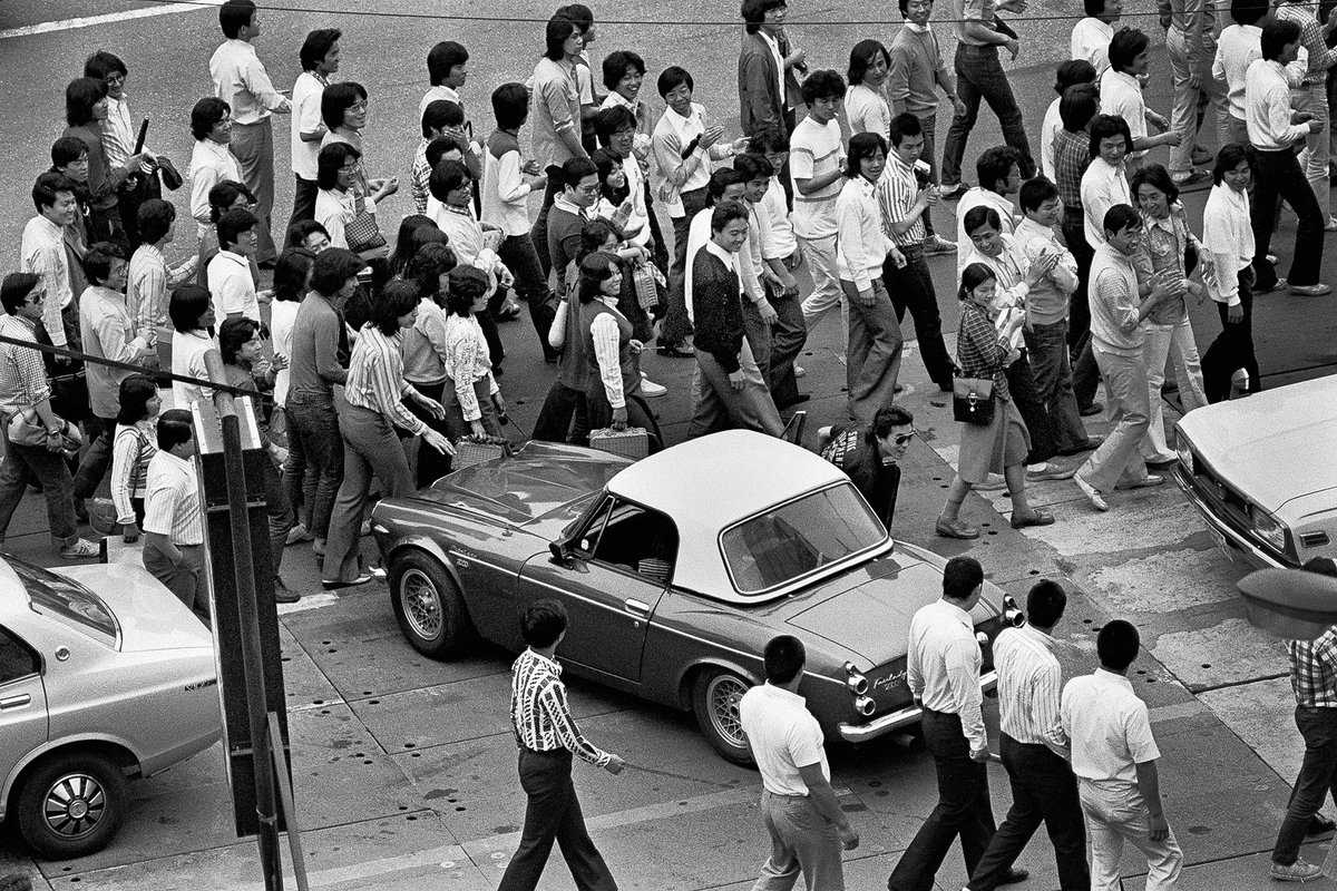 AlaoYokogi's tweet photo. @yokogi_alao NO NAME 1975年、青山通りの古いビルで、僕は写真家を始めた。 鉄板の道路。ユアーズの深夜のドーナッツ、 学生たちの列で、ダットサン・フェアレディ2000は出られない。 たまらず降りてきたのは、その年ブレークしたR.U。  Tokyo 1975.Aoyama A moment before a name becomes a name. https://t.co/vlowQTMCCo
