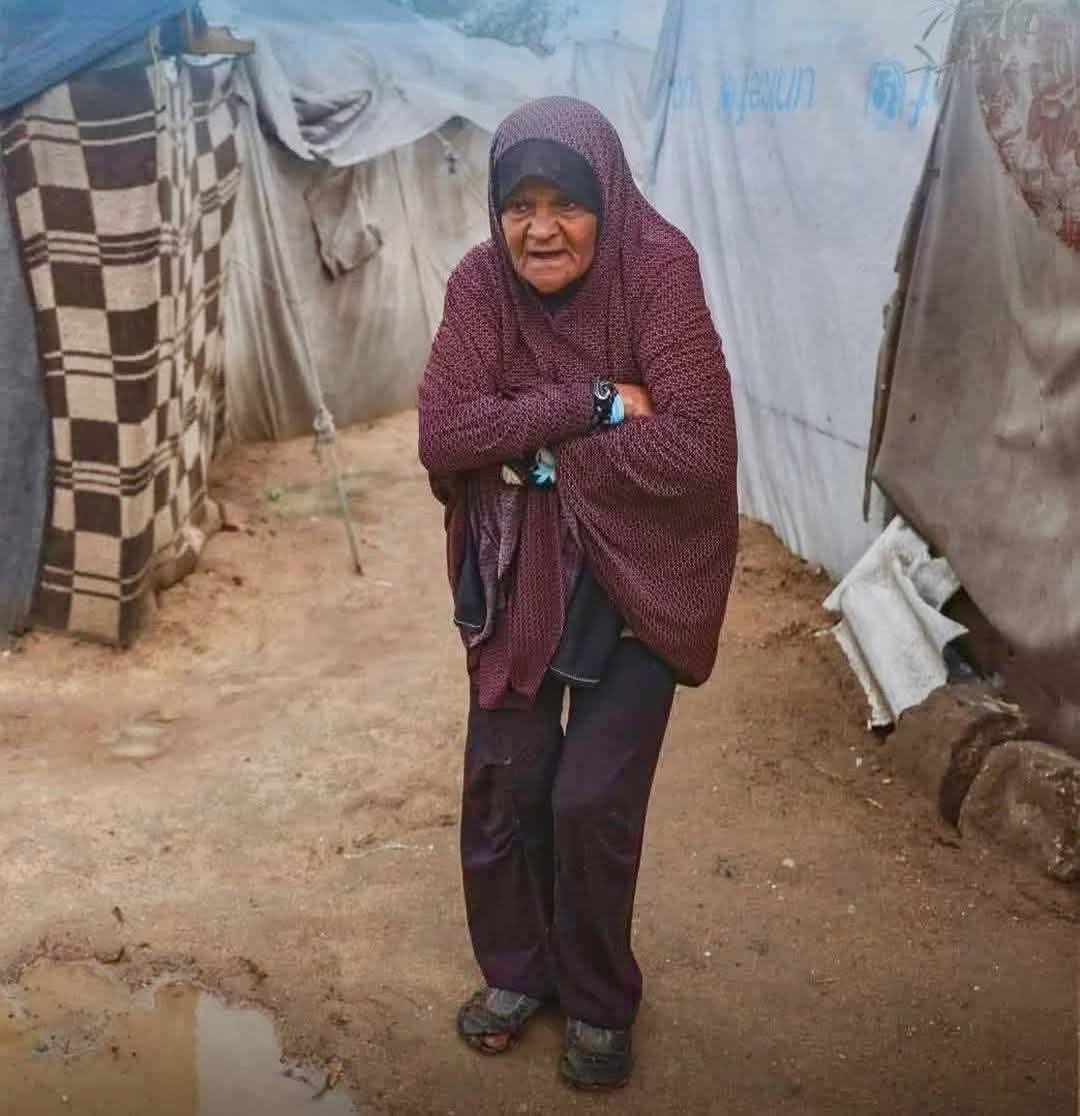 An elderly Palestinian woman stands alone in the open, shivering under the harsh cold after losing every form of shelter.
A scene that captures the immense humanitarian tragedy experienced by displaced families in Gaza amid severe weather conditions.
