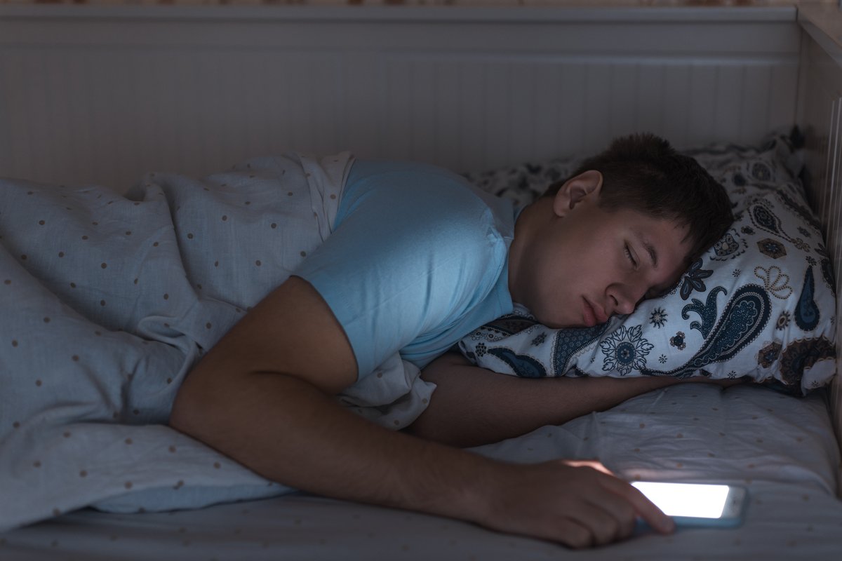 Do you sleep with your phone... meaning it's IN the bed with you?  Some do, but most keep it within arm's reach on a nightstand or table. 

- The Hawk and Tom Show