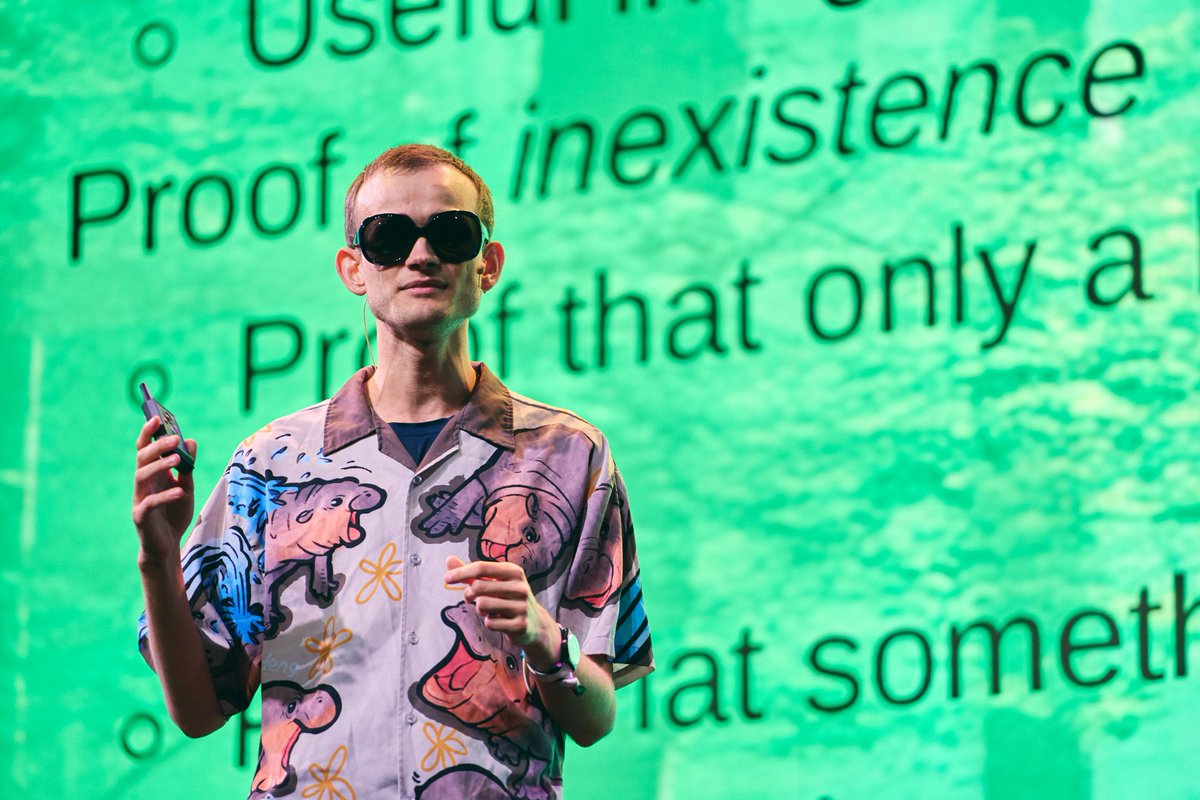 Devconnectで緑の背景スライドの前で話すVitalik Buterin