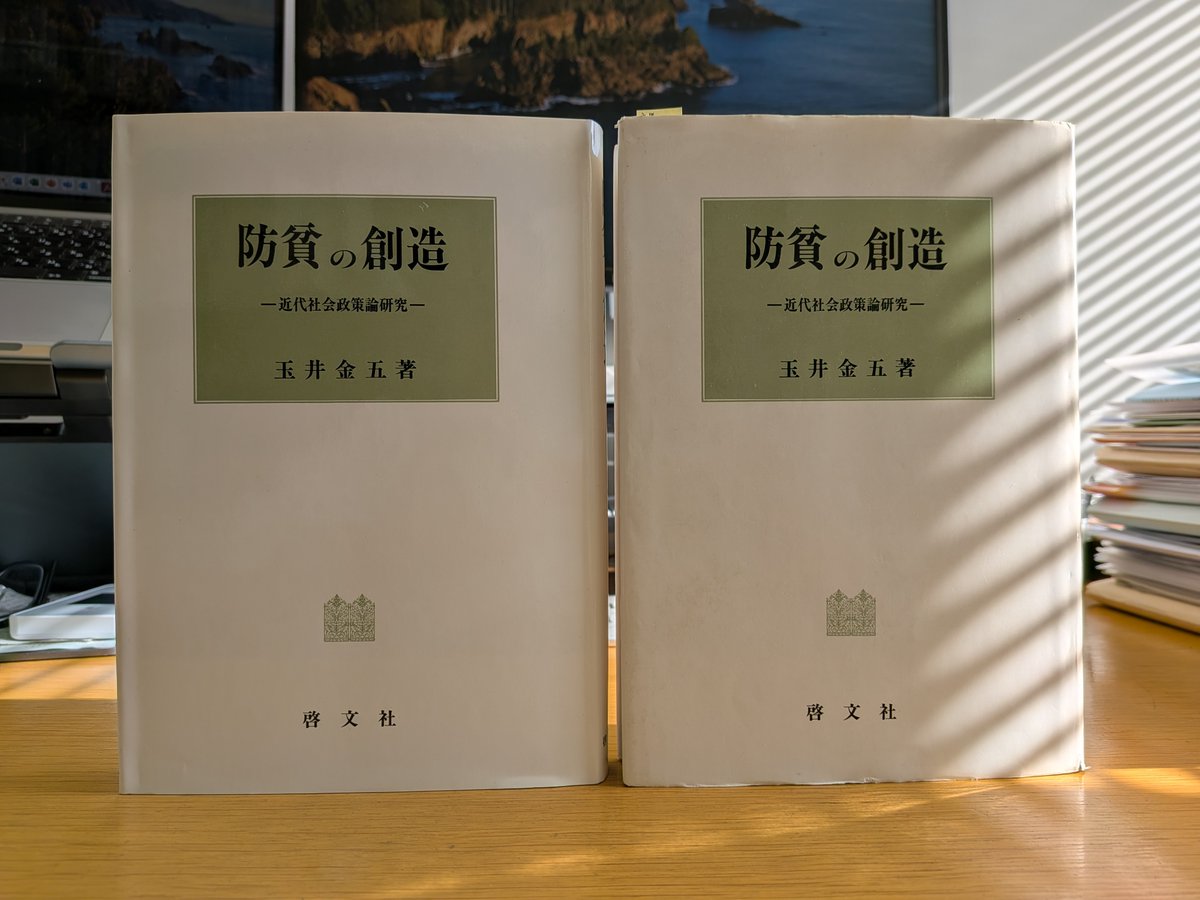 玉井金五先生の主著『防貧の創造――近代社会政策論研究』（啓文社、1992年）。左側は週末の偲ぶ会で分けていただいた新品。右側は大学院M1の1999年5月に購入し、同月の玉井先生の大学院講義の際にサインをいただいたもの。繰り返し読んできたことで本の背が割れ、新品に並べると形が変わっています。