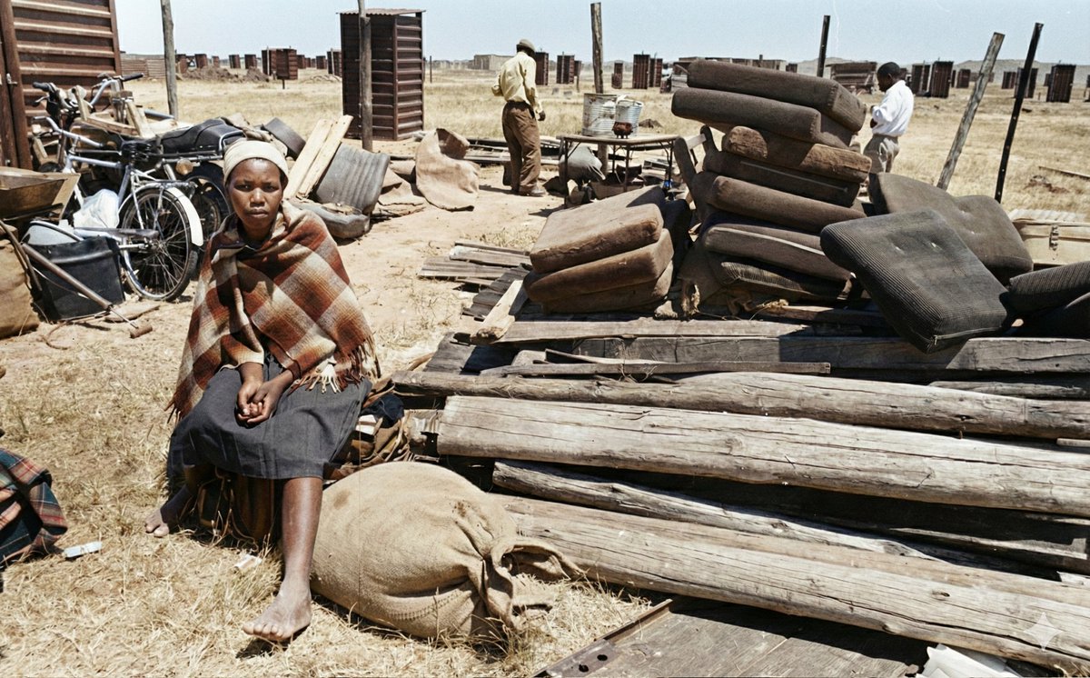 Forced removal of natives from their land by apartheid devils. 

38 years later, her children are expected to compete on equal footing with the children of the apartheid beneficiary who was given her land.