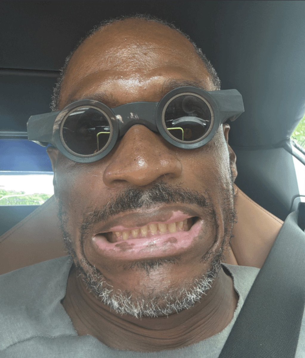 Arthur Hayes with a skeptical expression in a car, wearing distinctive round glasses