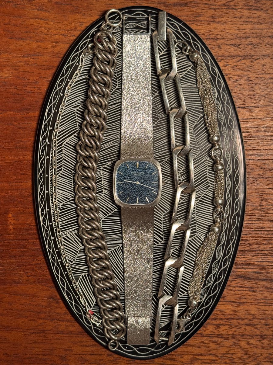 himaginism's tweet image. 2年連続のパテック・フィリップ。1970年代。自分の美学にグッときまくる美しさ。遠くから見ると紺色の文字盤。近くに寄ったり光が当たるとバンドと同じ質感の文字盤が浮き上がる。フェイスが28mmと小さめだがスクエアなので個人的に好きなサイズ感。40-70年代中心のアクセサリーと並べてみた。美しい。