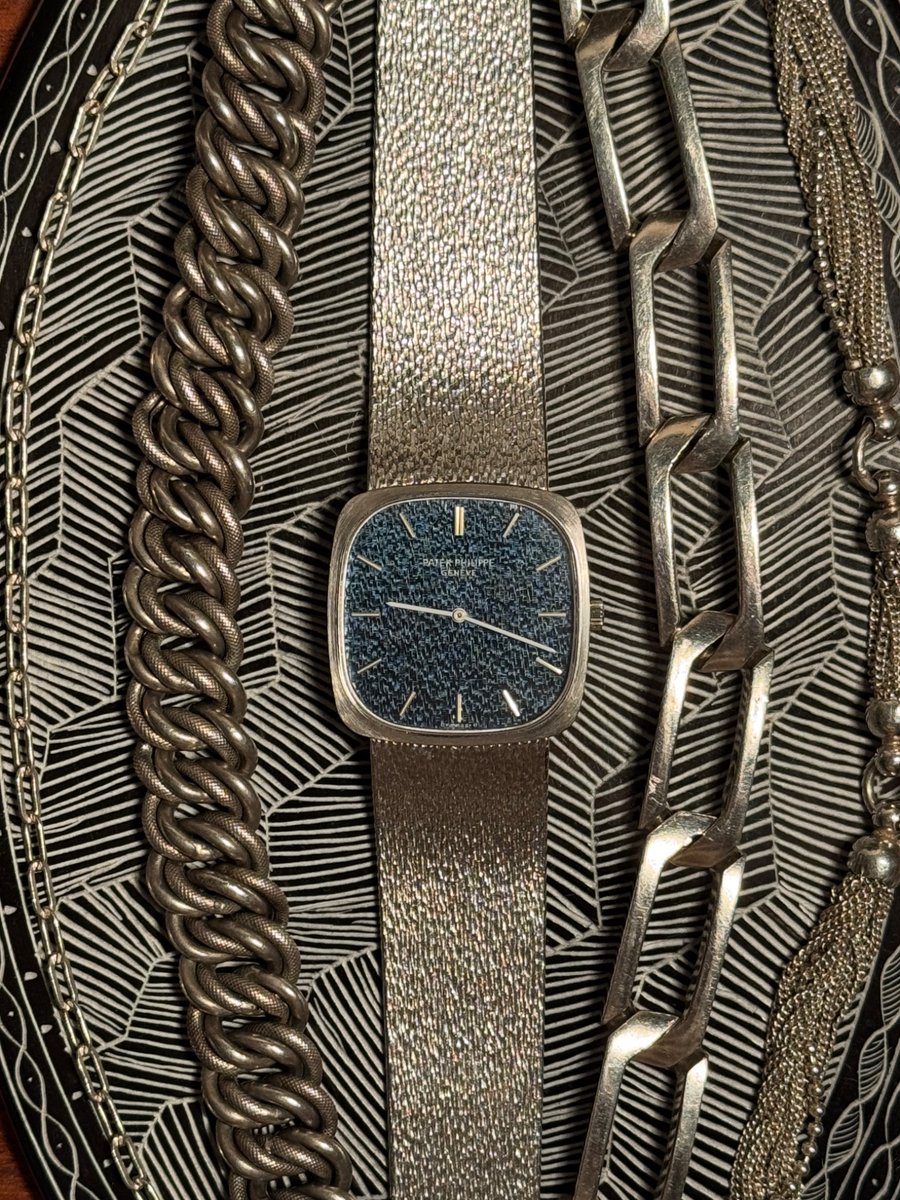 himaginism's tweet image. 2年連続のパテック・フィリップ。1970年代。自分の美学にグッときまくる美しさ。遠くから見ると紺色の文字盤。近くに寄ったり光が当たるとバンドと同じ質感の文字盤が浮き上がる。フェイスが28mmと小さめだがスクエアなので個人的に好きなサイズ感。40-70年代中心のアクセサリーと並べてみた。美しい。