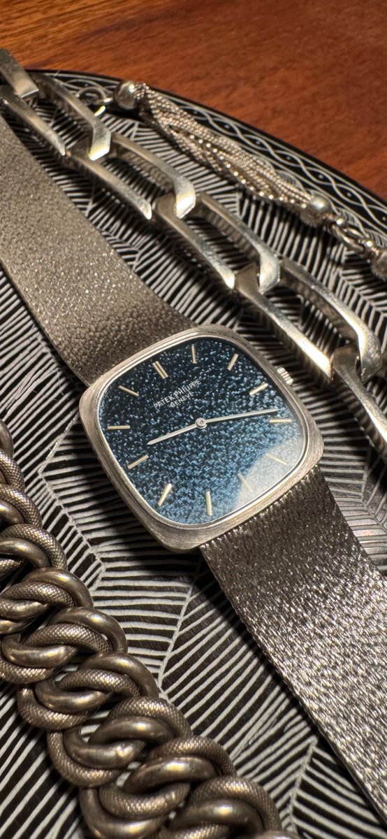 himaginism's tweet image. 2年連続のパテック・フィリップ。1970年代。自分の美学にグッときまくる美しさ。遠くから見ると紺色の文字盤。近くに寄ったり光が当たるとバンドと同じ質感の文字盤が浮き上がる。フェイスが28mmと小さめだがスクエアなので個人的に好きなサイズ感。40-70年代中心のアクセサリーと並べてみた。美しい。