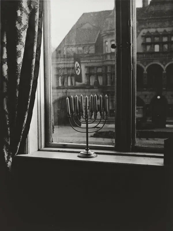 Hanukkah 1932, Kiel, Germany.

Rabbi Akiva and Rachel Posner placed their menorah on the windowsill across from a building draped in a Nazi swastika flag.

Rachel Posner took a picture of her Menorah and wrote on it:  "Juda verrecke, ‘Juda lebt ewig,’ antwortet das Licht.”