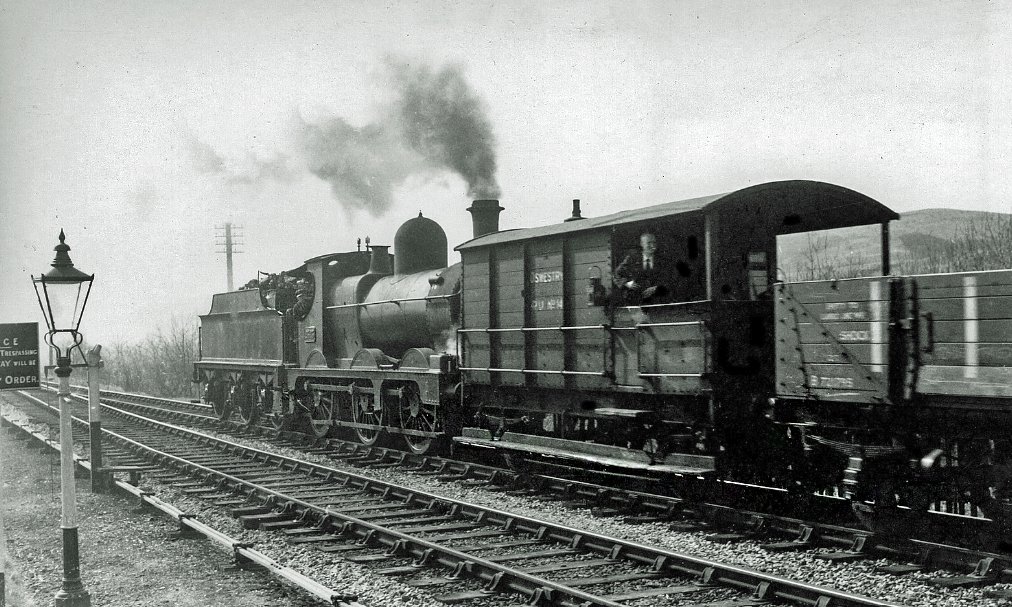 Cemmes Road, Powys, 12th of April 1960

Class 0-6-0 No 2323 banks the 2 o'clock Machynlleth to Oswestry freight into the loop at Cemmes Road.

N. Harrop