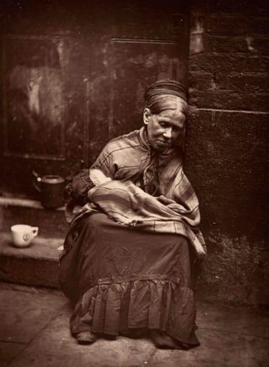 Dr_TheHistories's tweet photo. “The Crawlers”, 1877. ‘The Crawlers’ were the lowest of the British poor. This elderly widow is sitting outside a tailor’s shop, holding a baby while its mother works. She was given a cup of tea and a slice of bread daily in return.

The photograph titled “The Crawlers” was taken in 1877 and captures one of the harshest realities of Victorian poverty in London. The term “crawlers” referred to some of the most destitute people in society — often the elderly, widowed, or disabled, who were too frail to work and forced to rely on scraps of charity to survive. They were called “crawlers” because many were so weakened by hunger, disease, or age that they could only move slowly, often crawling or dragging themselves along the streets.

In this haunting image, an elderly widow sits outside a tailor’s shop, cradling an infant. The baby’s mother, likely a working-class woman struggling to make ends meet, left her child in the widow’s care while she labored inside. The widow’s payment for this exhausting responsibility was meager: a cup of tea and a slice of bread a day. Such arrangements were common, as survival for the poorest relied on fragile networks of mutual aid and the charity of others.

This photograph is more than a snapshot, it is a window into the crushing inequalities of Victorian society. While industrial Britain was generating immense wealth, many of its citizens were trapped in cycles of poverty, living day to day on the edge of survival.

Social reformers later used photographs like this as evidence to push for changes in housing, sanitation, and welfare laws, laying the groundwork for Britain’s eventual social safety nets.

© Historic UK 

#drthehistories