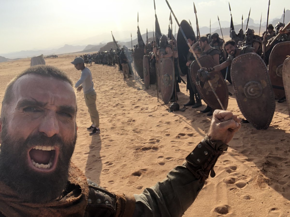 sharlto's tweet photo. Back in Saudi! 
4  years ago I spent 5 months in this desert with a crazy-talented crew from 38 countries: camels, sunsets, dune BBQs, and one of the last war epics shot fully on location. 
(Someone pranked Sir Ben Kingsley?) DESERT WARRIOR premieres tonight at  #RedSeaIFF https://t.co/v8oKE2vD3S