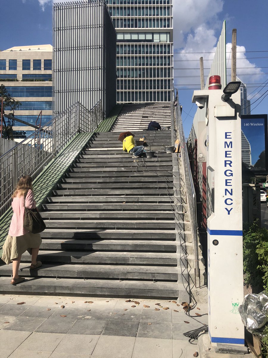 Stairway to nowhere, Wireless Road entrance to Lumpini Park, Bangkok. The staircase stone mason is listening to Burmese pop music on her phone while she works. <a href="/Rajprasong_News/">Sean Boonpracong</a>