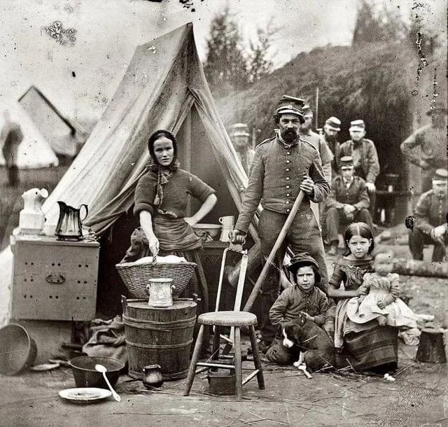 A woman and children join soldiers of the 31st Pennsylvania Regiment in a Union Army camp near Washington during the Civil War.
