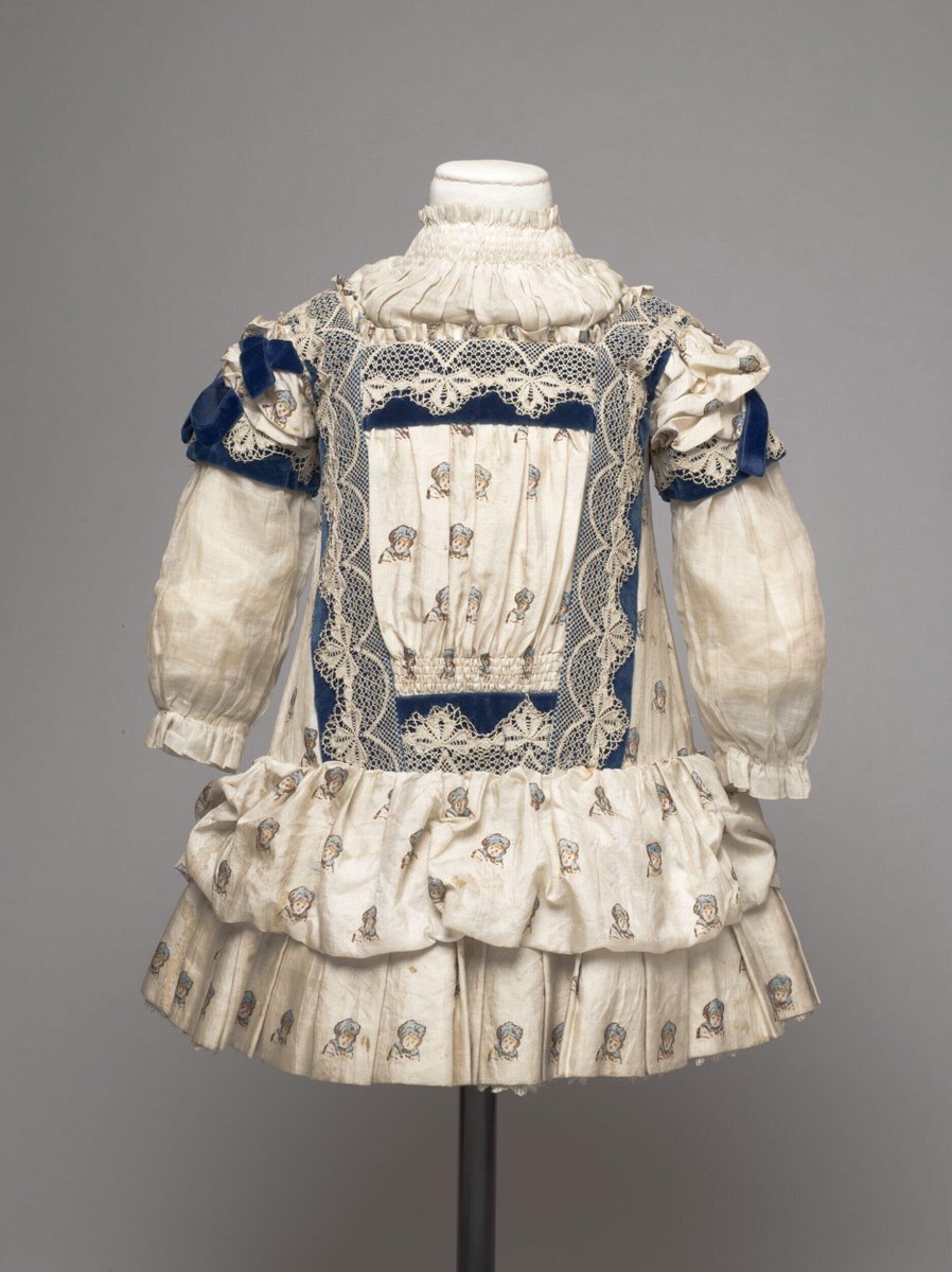wikivictorian's tweet image. Girl's dress of ivory-coloured printed silk trimmed with machine-made lace and blue velvet; England, ca. 1885. Victoria &amp;amp; Albert Museum. 

This dress is somewhat unusual in its fabric and trimmings. The printed silk shows some irregularities, and may have been a sample fabric.…