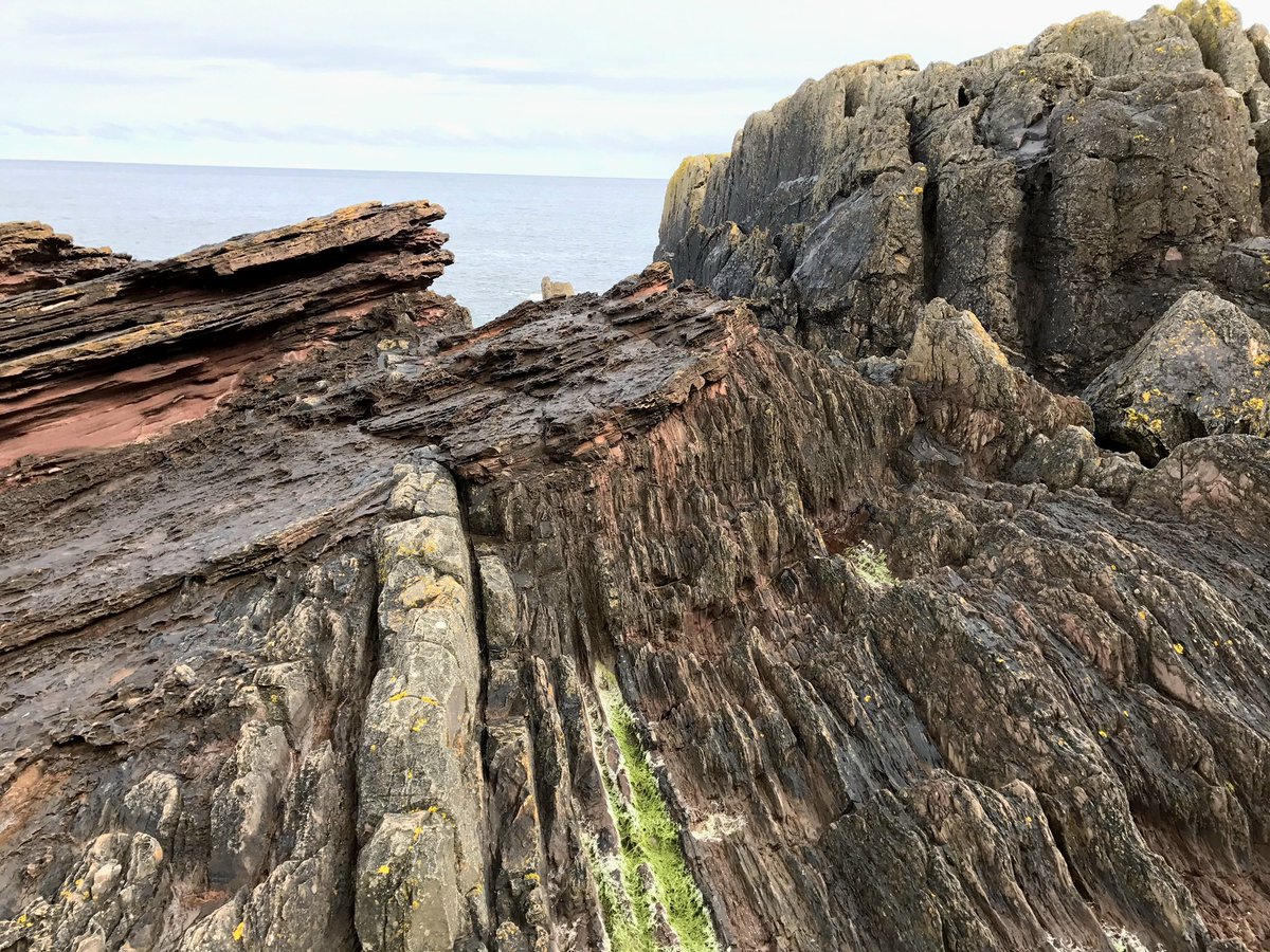 geologyBits's tweet photo. 🟥 ⛏️ Siccar Point
lies on the Berwickshire coast of Scotland, roughly fifty kilometers east of Edinburgh.
❤️ 🔁 #HuttonsUnconformity #SiccarPoint
🎞 @play_north
▶️ It is celebrated for Hutton’s Unconformity, a striking angular unconformity where nearly vertical grey Silurian greywackes are overlain by gently dipping red Devonian Old Red Sandstone.
The sharp contact reveals a missing interval of around seventy million years and gave James Hutton the field evidence he needed in 1788 to establish the concept of deep geological time.
▪️ The older rocks are Silurian turbiditic sandstones and siltstones, laid down in deep marine basins as continents closed during the Caledonian Orogeny.
They were intensely folded and tilted until almost vertical.
▪️ After mountain-building ceased, uplift and prolonged erosion planed off the highlands and removed all traces of Late Silurian and Early Devonian strata, creating a landscape of rugged relief.
▪️ In Middle Devonian times, rivers draining the worn-down Caledonian mountains deposited coarse continental sediments directly onto the eroded Silurian surface.
▪️ These red conglomerates and sandstones filled paleovalleys cut into the older rocks.
Later burial, gentle tilting, and eventual exposure by coastal erosion produced the dramatic cliff section seen today.