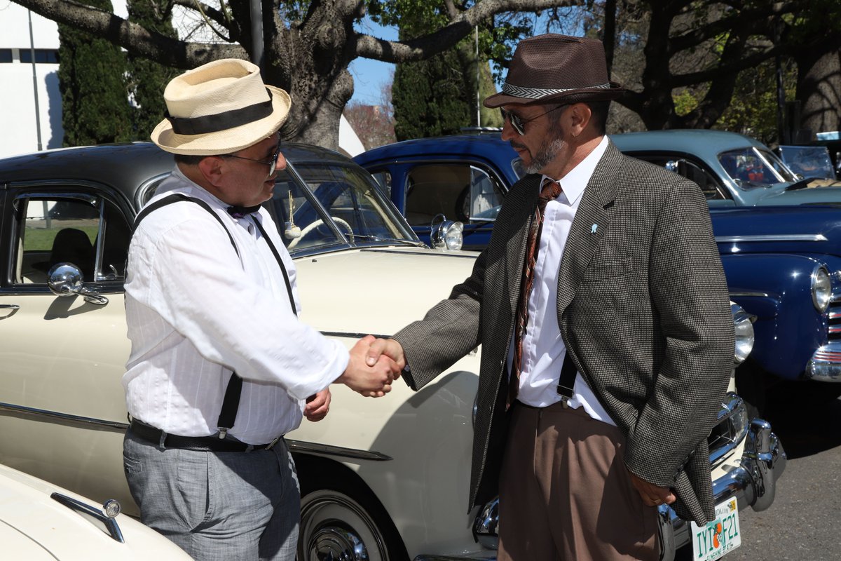 Two sharply dressed gents sealing a deal with a handshake by a cream vintage beauty in sunny Rosario. The kind of moment that makes you want to dust off your best fedora and join us next year on September 27th.  

📸 @ruben_alb_  
🌎 Argentina, Rosario