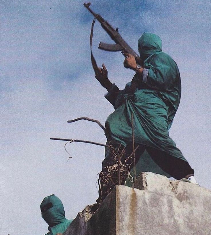 Two fighters from the Free Syrian Army wearing makeshift green camouflage robes. 

Aleppo, Syria 2012