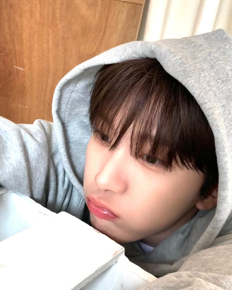 Grey fabric frames his face as he pouts softly, leaning against the edge of the room like he’s waiting for something to shift. Light falls gently across his features, turning that small sulk into a calm kind of honesty—simple, real, and impossible to overlook.