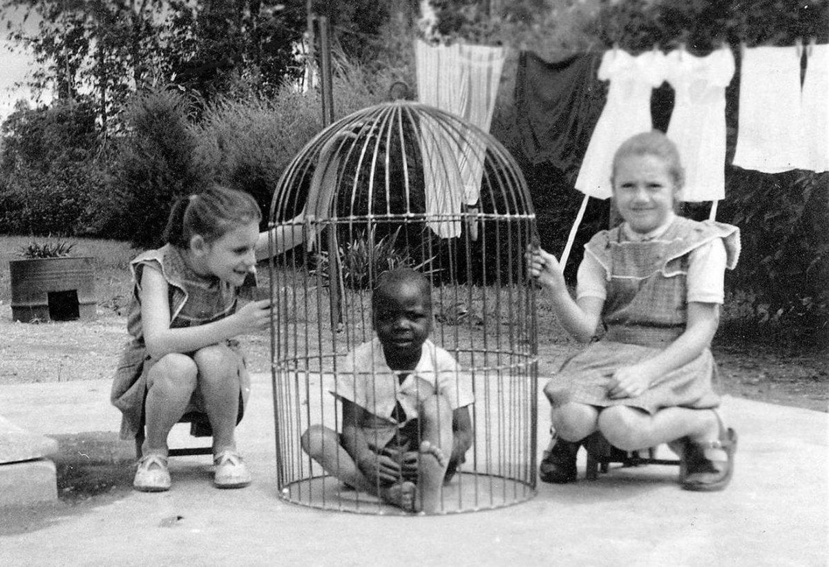 islamicize's tweet image. African boy in a cage watched by two white girls, Belgian Congo