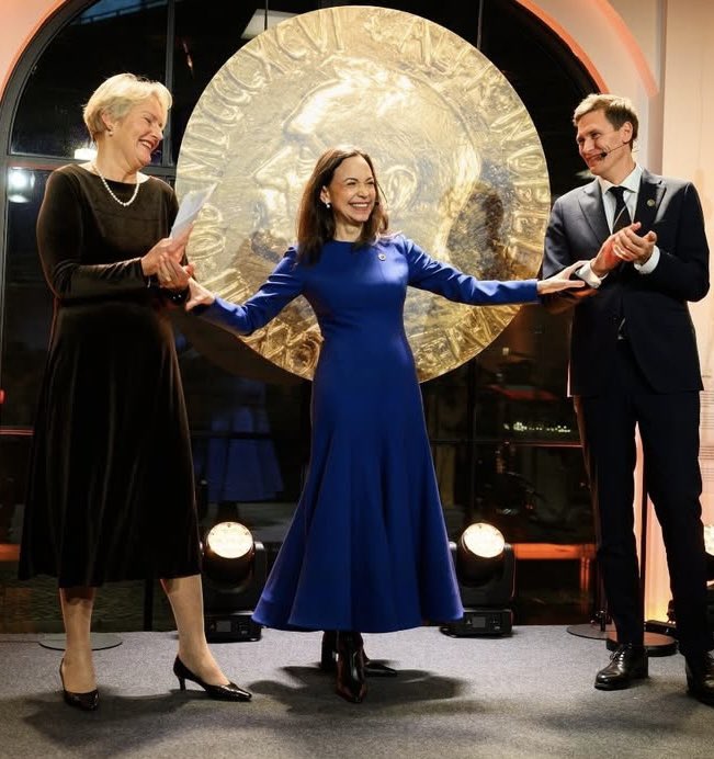 ¡DESPAMPANANTE! No se puede creer. Esto parece sacado de una película. Dos días antes, la Nobel de La Paz estaba a la deriva en un mar tormentoso, como parte de su travesía para escapar de los terroristas del Cartel de Los Soles, y ahora luciendo como una Reina de azul. Cuanto