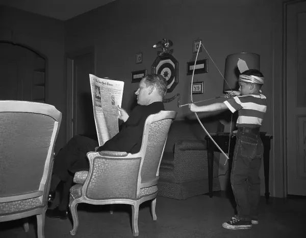 PresArchive's tweet image. Al Gore Jr. points a toy bow and arrow at Sen. Al Gore Sr.'s back.